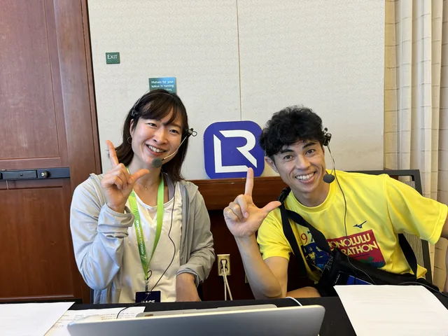 A LIVERUN guest session at the broadcast desk: a guest in a Honolulu Marathon shirt beside a member of the LIVERUN team, both on headset microphones, with the LIVERUN mark on the wall behind them